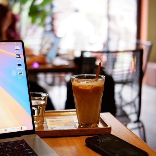 Refreshing iced coffee placed on a wooden table in a contemporary café setting, perfect for work or leisure.